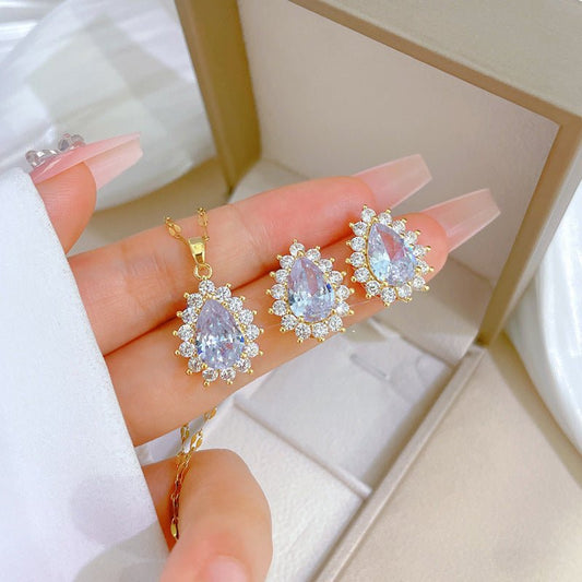 Gold jewelry set with pear-shaped gemstones on a hand
