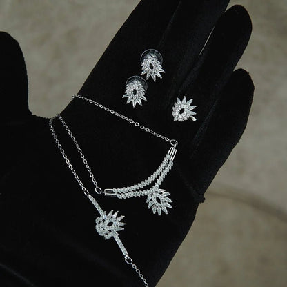 Silver jewelry set with necklace and earrings on a black glove against a neutral background