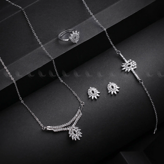Silver jewelry set including necklace, ring, and earrings on a dark surface.