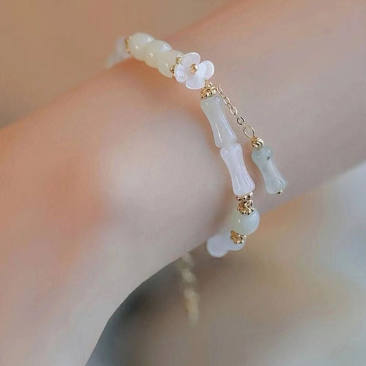 Delicate bracelet with floral and bamboo design on a blurred background