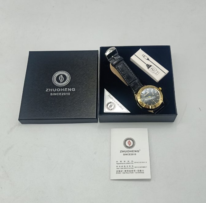 Watch with black leather strap and gold case in a 'Zhuoheng' branded box on a light gray background.