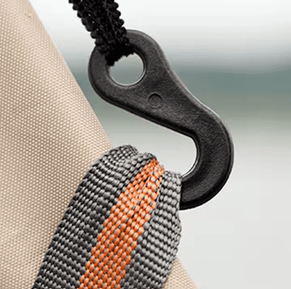 Close-up of a black carabiner attached to a beige fabric surface with a blurred background.