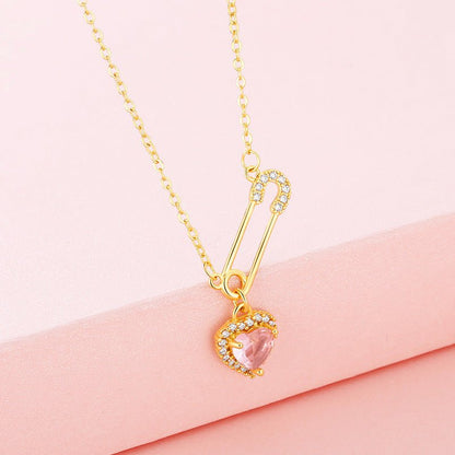 Gold necklace with a pink heart-shaped pendant on a pink background