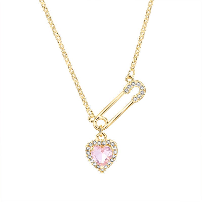 Gold safety pin necklace with a pink heart pendant on a white background