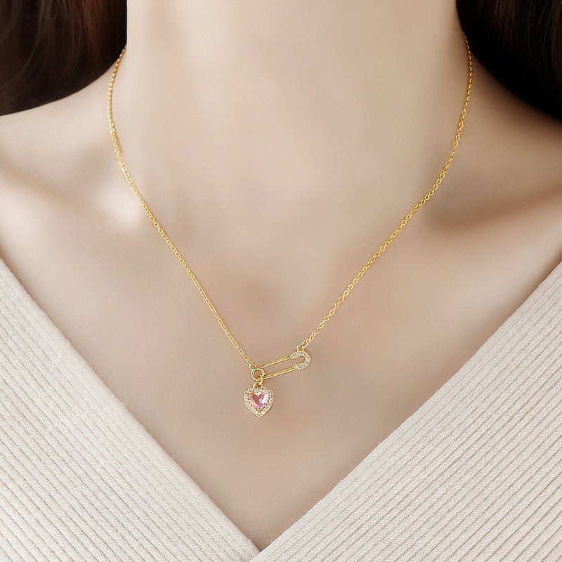 Gold necklace with a heart-shaped pink pendant on a mannequin