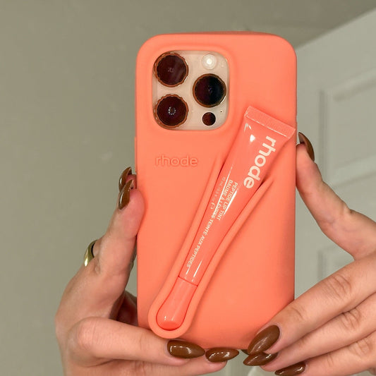 Coral phone case with a zipper pocket held by hands against a neutral background