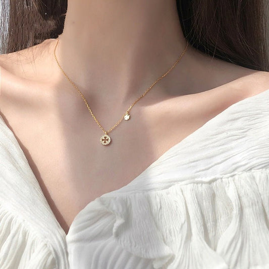 Gold necklace with a small pendant on a person wearing a white top.