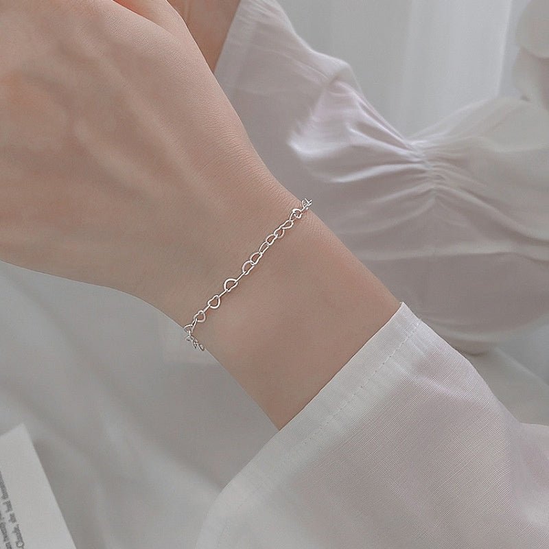 Silver bracelet on a wrist with a blurred white background