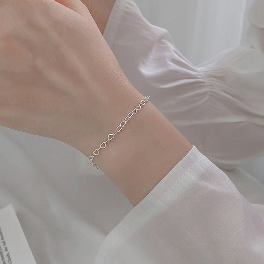 Silver bracelet on a wrist with a blurred white background