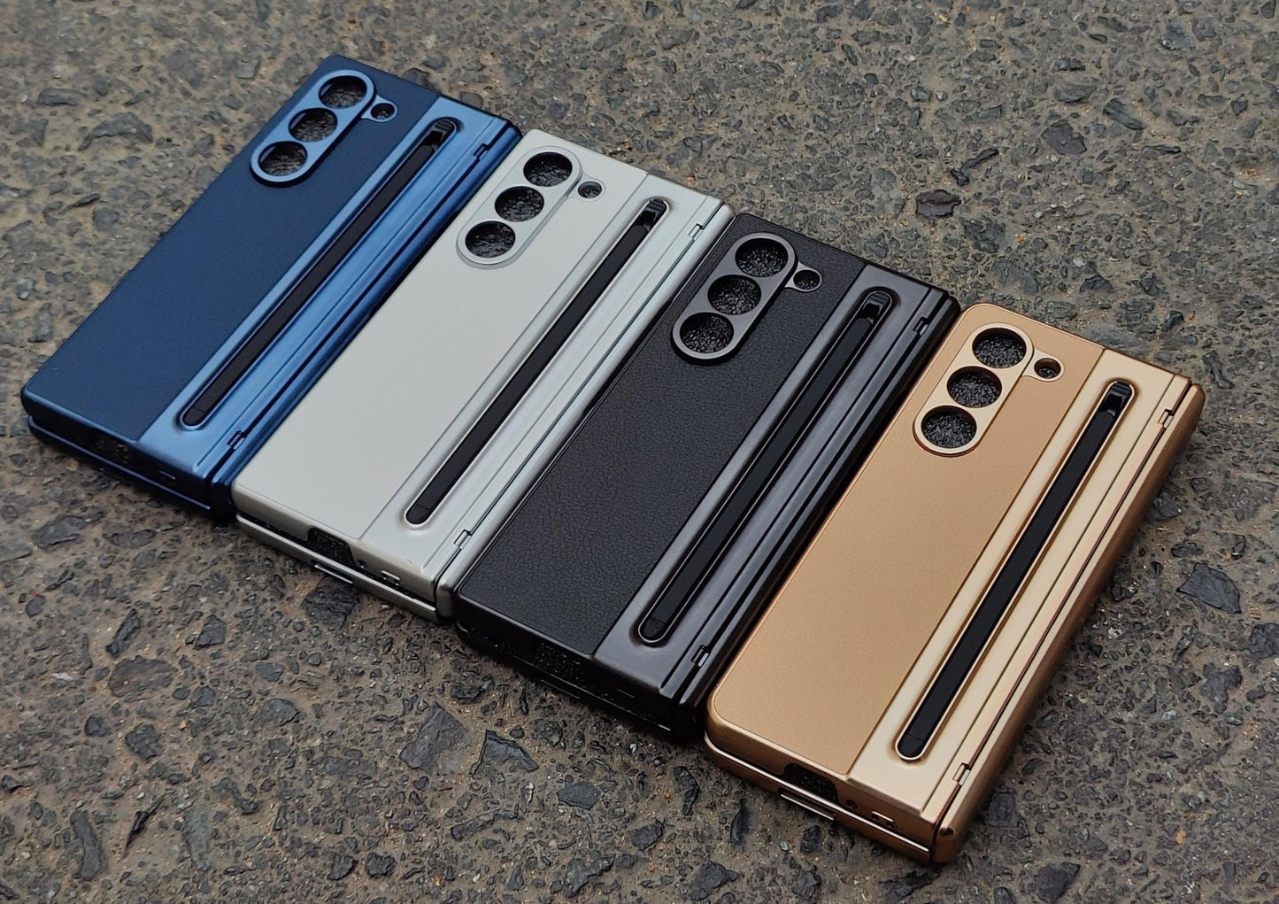 Four smartphone cases in blue, gray, black, and gold on a textured surface