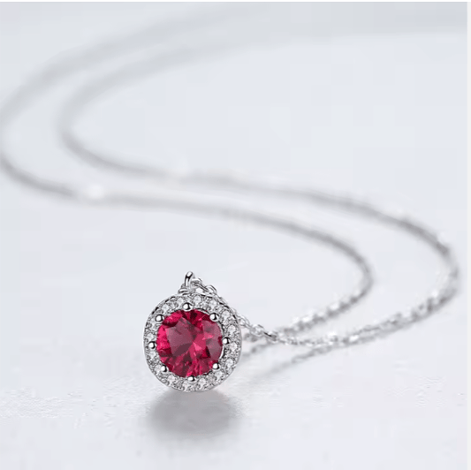 Silver necklace with a red gemstone pendant on a light gray background