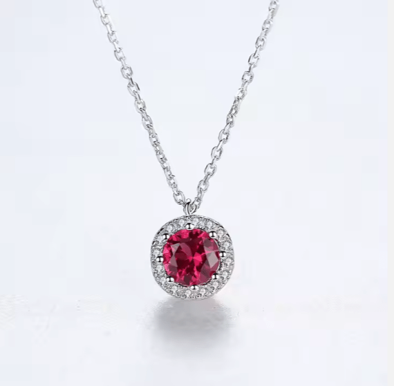 Silver necklace with a red gemstone pendant on a white background