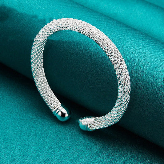 Silver bracelet on a teal fabric background