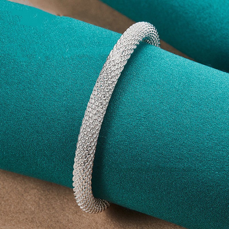 Silver bracelet on a teal cushion