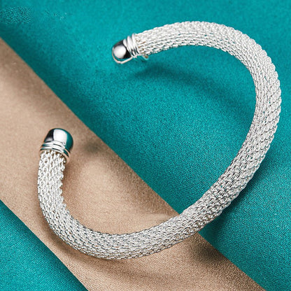 Silver mesh bracelet on a turquoise and beige fabric background