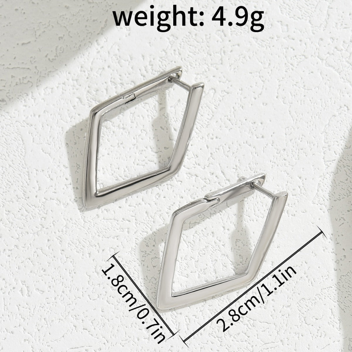 Pair of silver geometric hoop earrings on a textured white surface with weight and dimensions displayed.