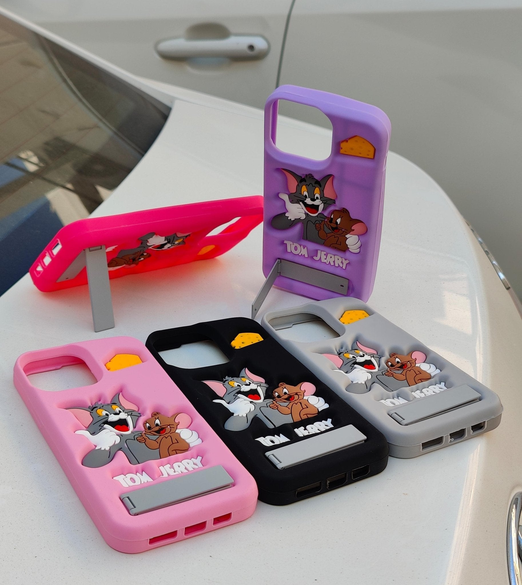 Four colorful phone cases with cartoon characters on a white surface.