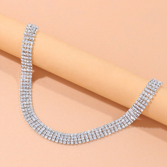 Silver necklace with clear stones on a beige background