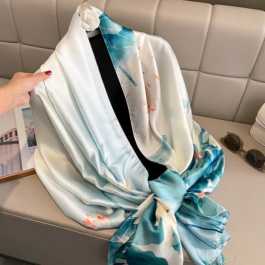 Scarf with blue and white design draped over a mannequin on a light-colored couch.