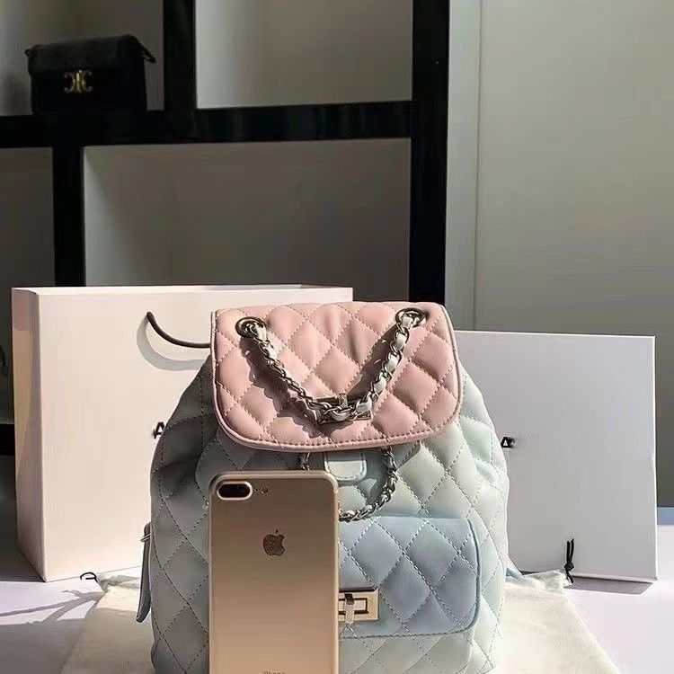 Quilted handbag with chain detail next to a smartphone on a reflective surface.