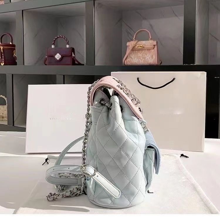 Quilted handbag with chain detail on a white surface, with a display of similar bags in the background.