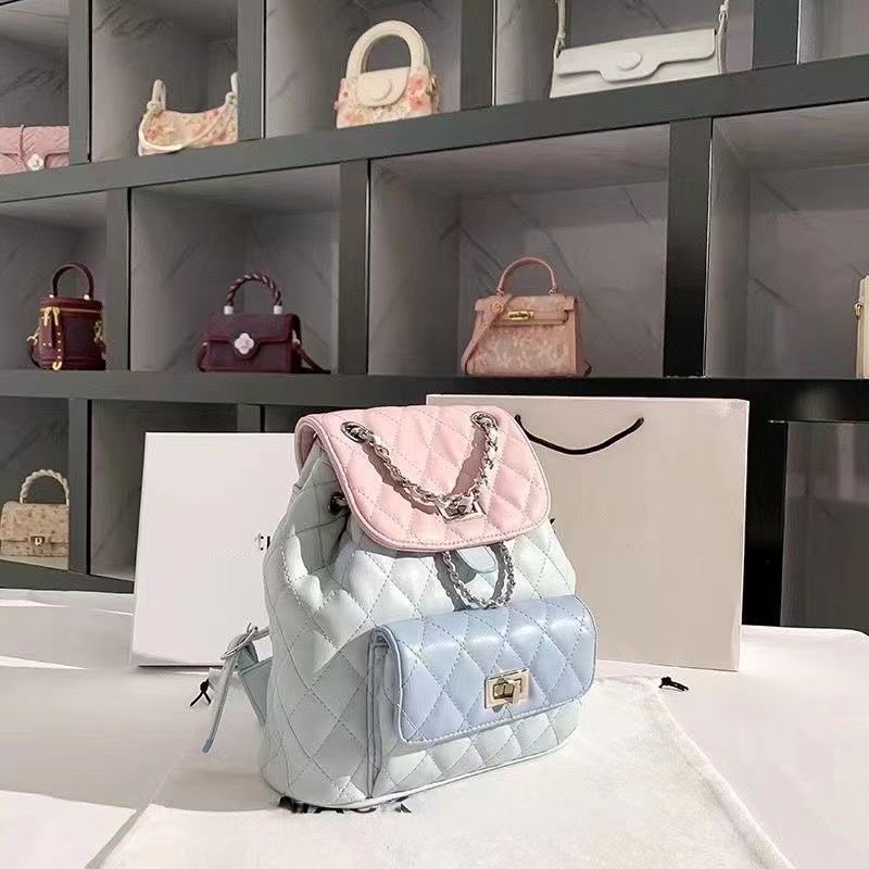 Quilted backpack with pink top handle and silver chain on a white surface with shelves of handbags in the background.