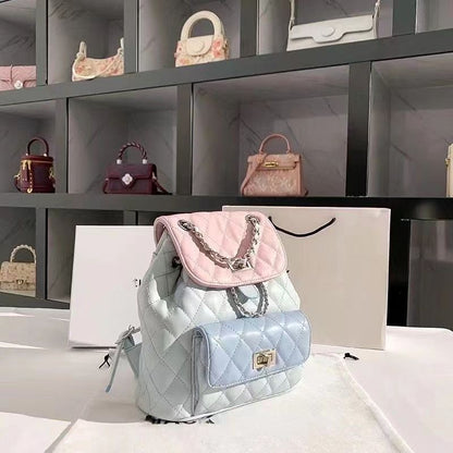 Quilted backpack with pink top handle and silver chain on a white surface with shelves of handbags in the background.