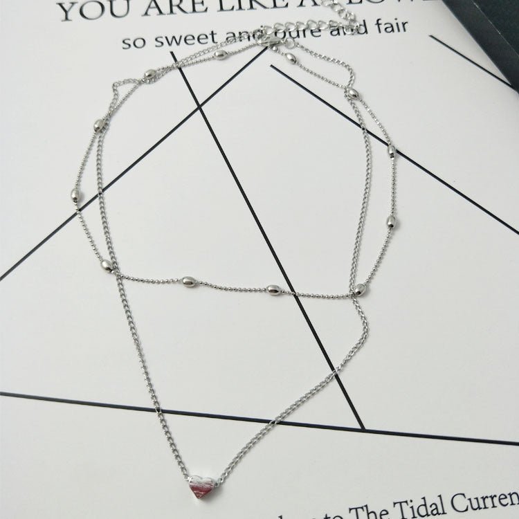 Silver necklace with a pink pendant on a printed paper background