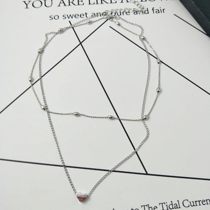 Silver necklace with a pink pendant on a printed paper background
