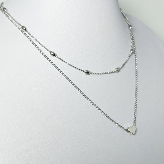 Silver necklace with a heart pendant on a mannequin bust against a white background
