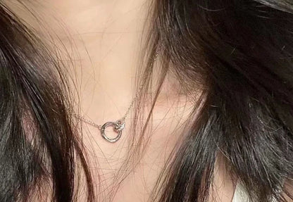 Necklace with a small circular pendant worn by a person with dark hair.
