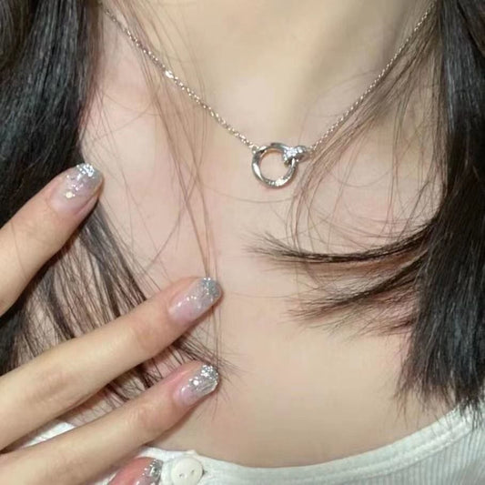 Close-up of a silver necklace with a unique pendant worn by a person.