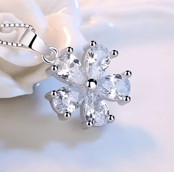 Silver necklace with a flower-shaped pendant on a soft white background